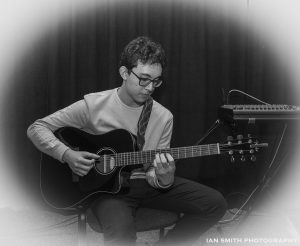 Izzy, Trust Music Beneficiary, playing the guitar